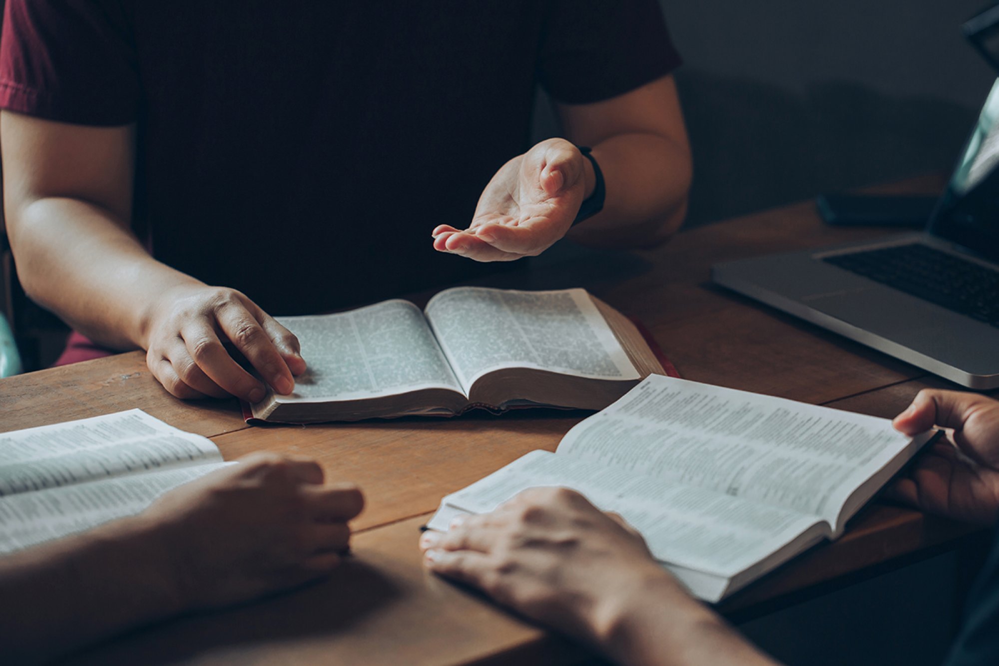 Nærbilde av to par hender med hver sin bibel