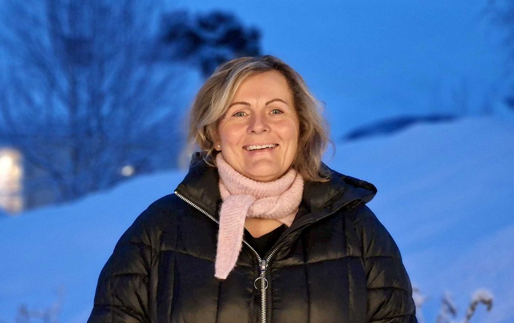 Dame med boblejakke står ute i vinterlandskap og smiler mot kamera