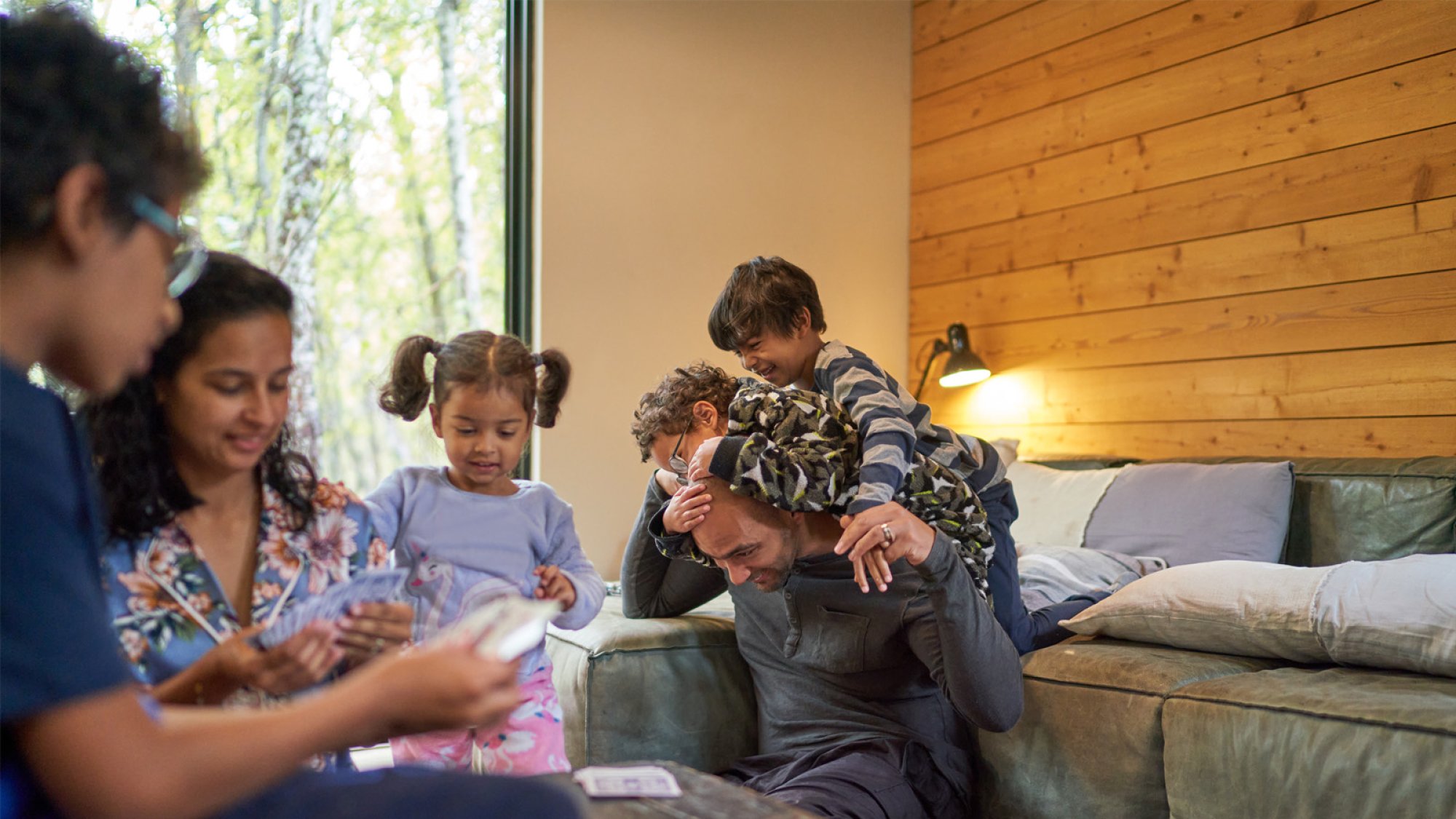 En familie med foreldre, en ungdom og barn leker sammen og hjelper hverandre.