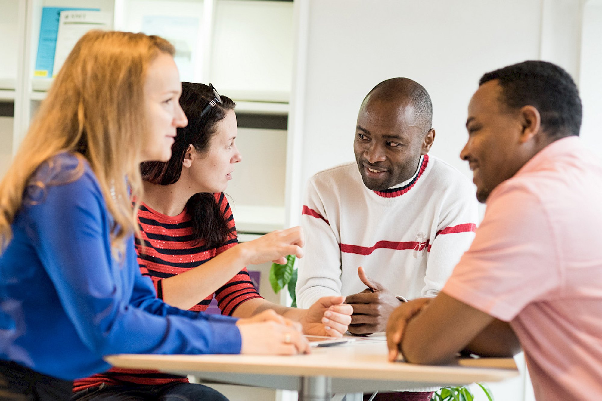 En gruppe studenter sitter rundt et bord og diskuterer