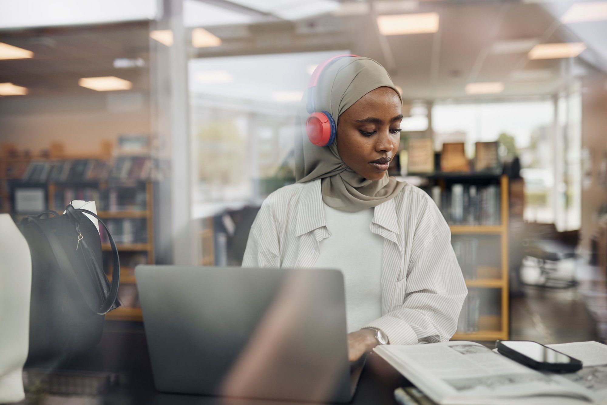 En kvinnelig student med hodetelefoner jobber på en datamskin